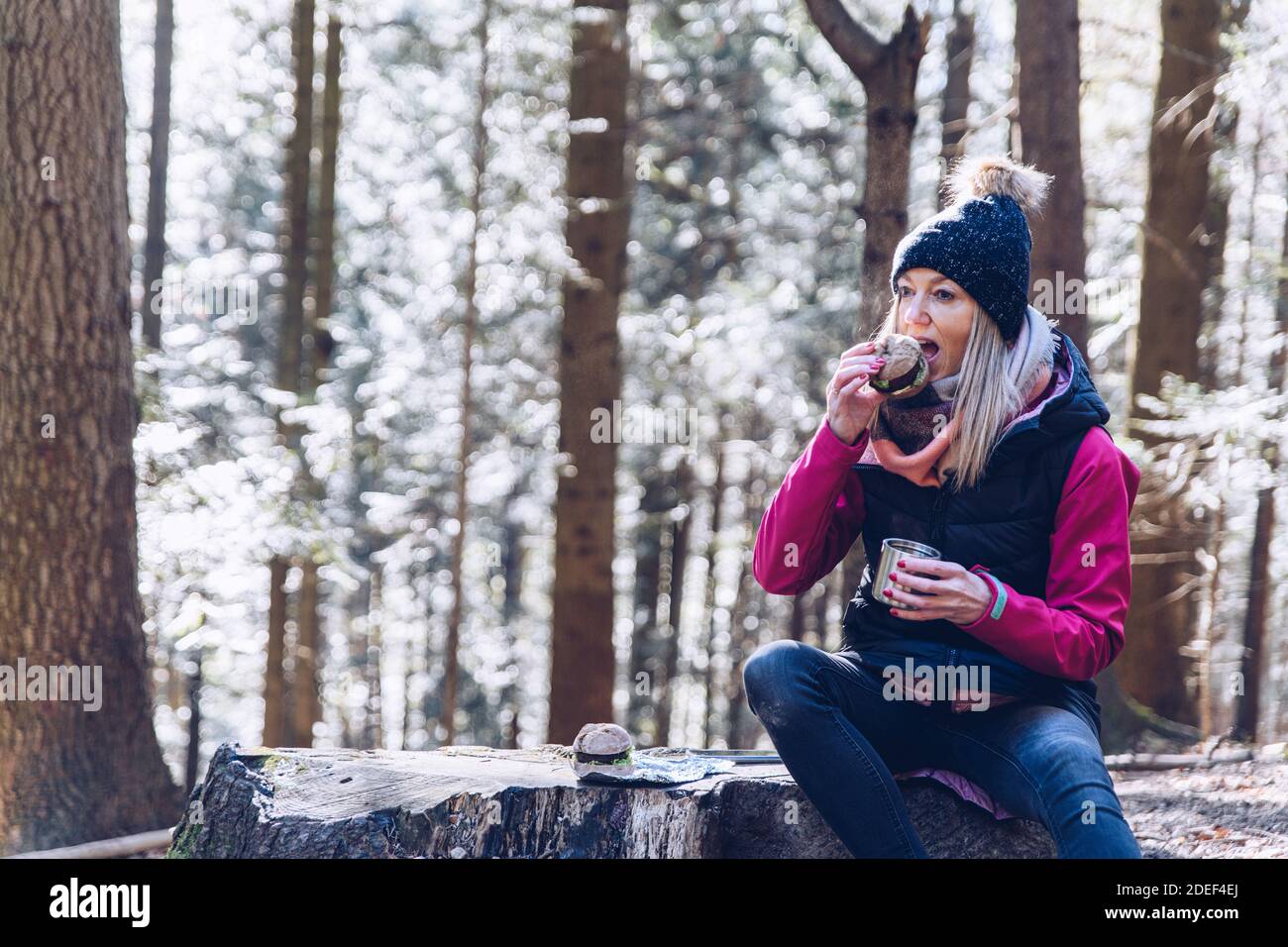 Ein Tourist auf einer Wanderung im Herbstwald auf einem Bergweg ruht, essen und trinken heißen Tee. Stockfoto