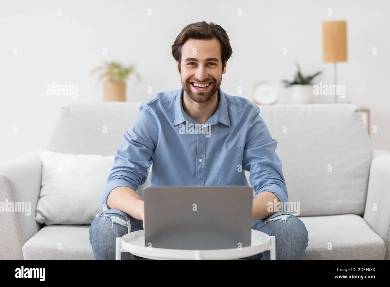 Mann am Laptop-Computer arbeitet online und lächelt zu Hause Stockfoto