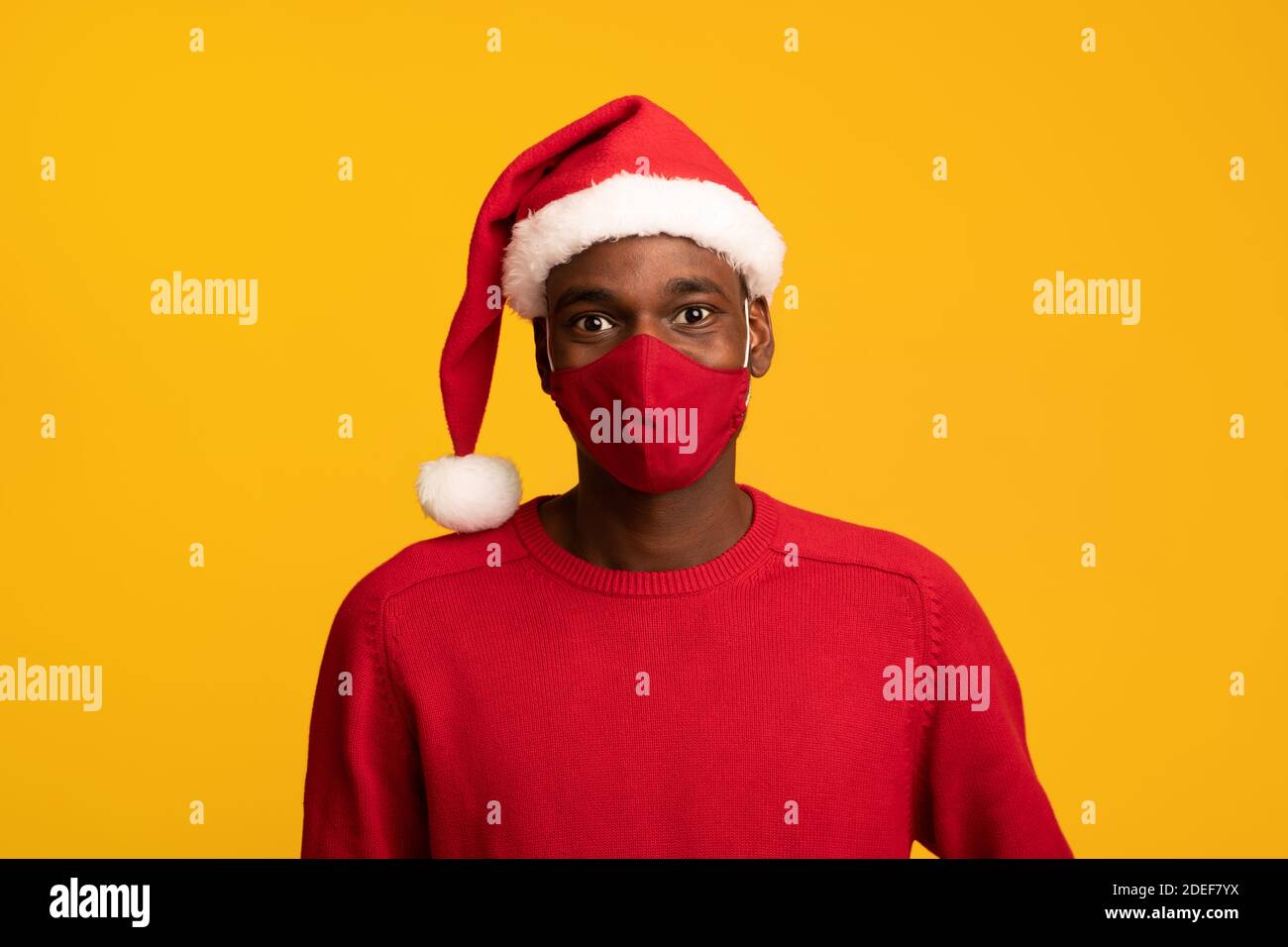 Coronavirus Weihnachten. Junger Schwarzer Mann Trägt Prätektive Gesichtsmaske Und Weihnachtsmütze Stockfoto
