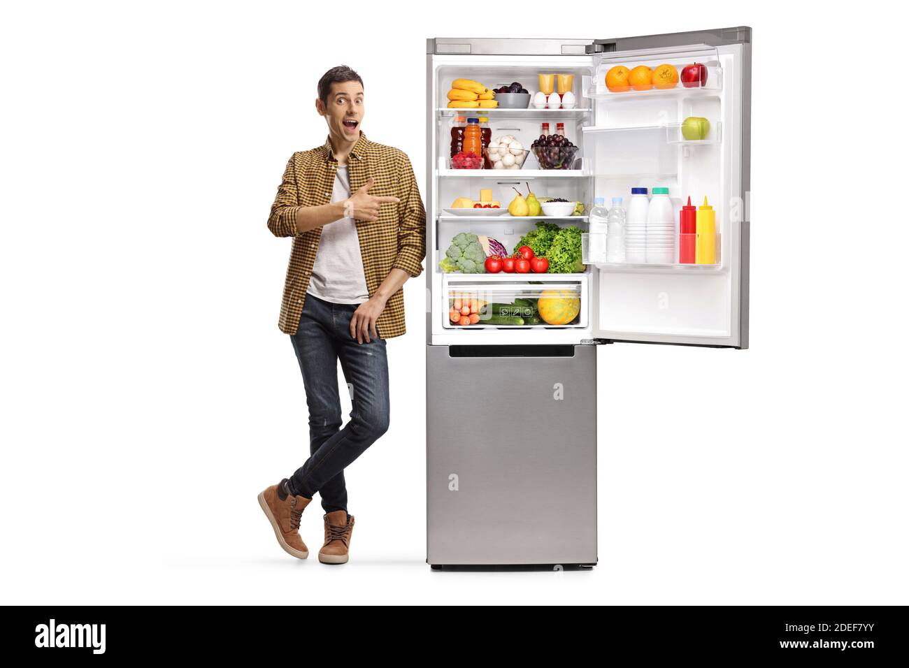 In voller Länge Porträt eines jungen Mannes zeigt auf ein Kühlschrank mit Essen isoliert auf weißem Hintergrund Stockfoto