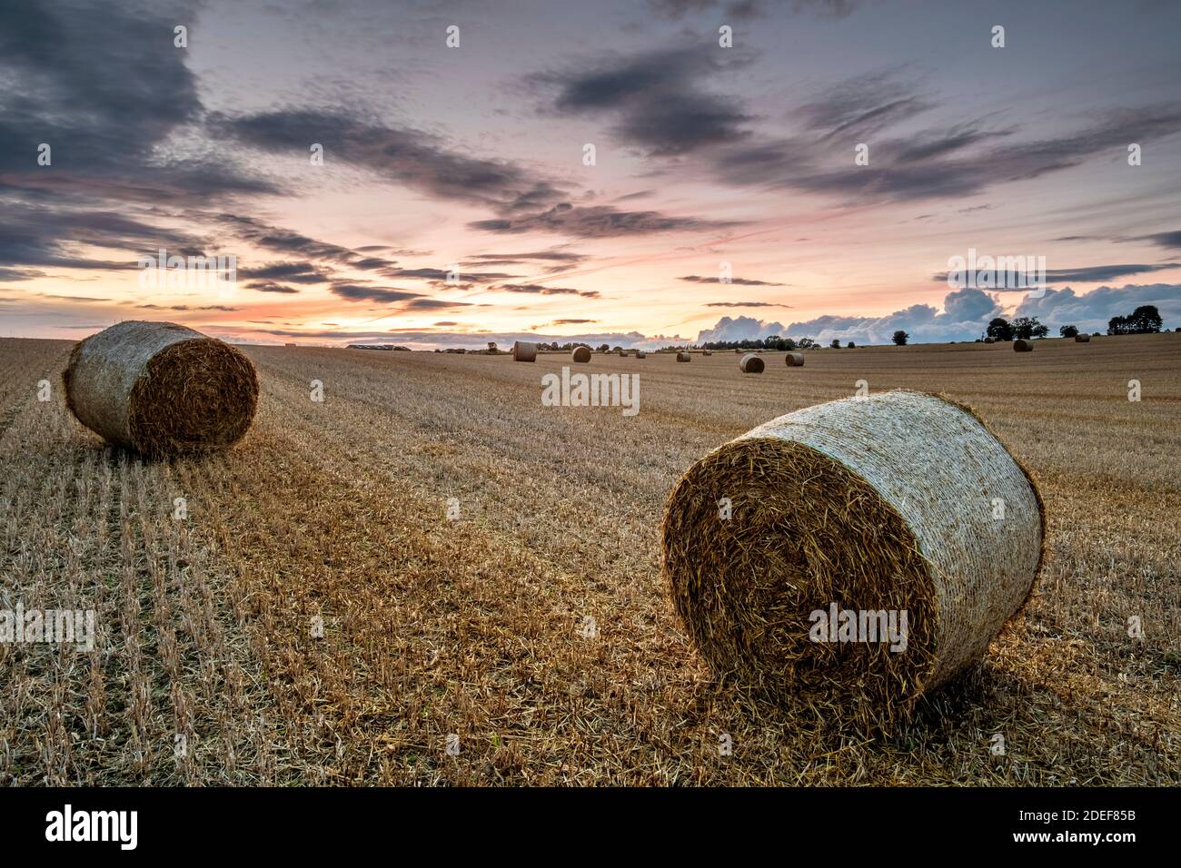 Sonnenuntergänge über einem Strohballen-Feld Stockfoto