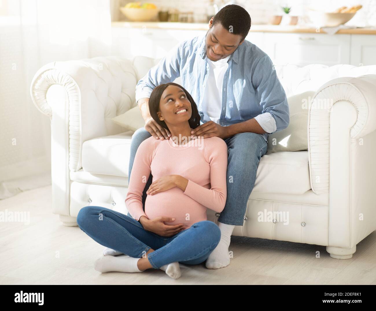 In voller Länge Porträt von schönen schwarzen Mann geben Massage zu Seine schwangere Frau zu Hause Stockfoto
