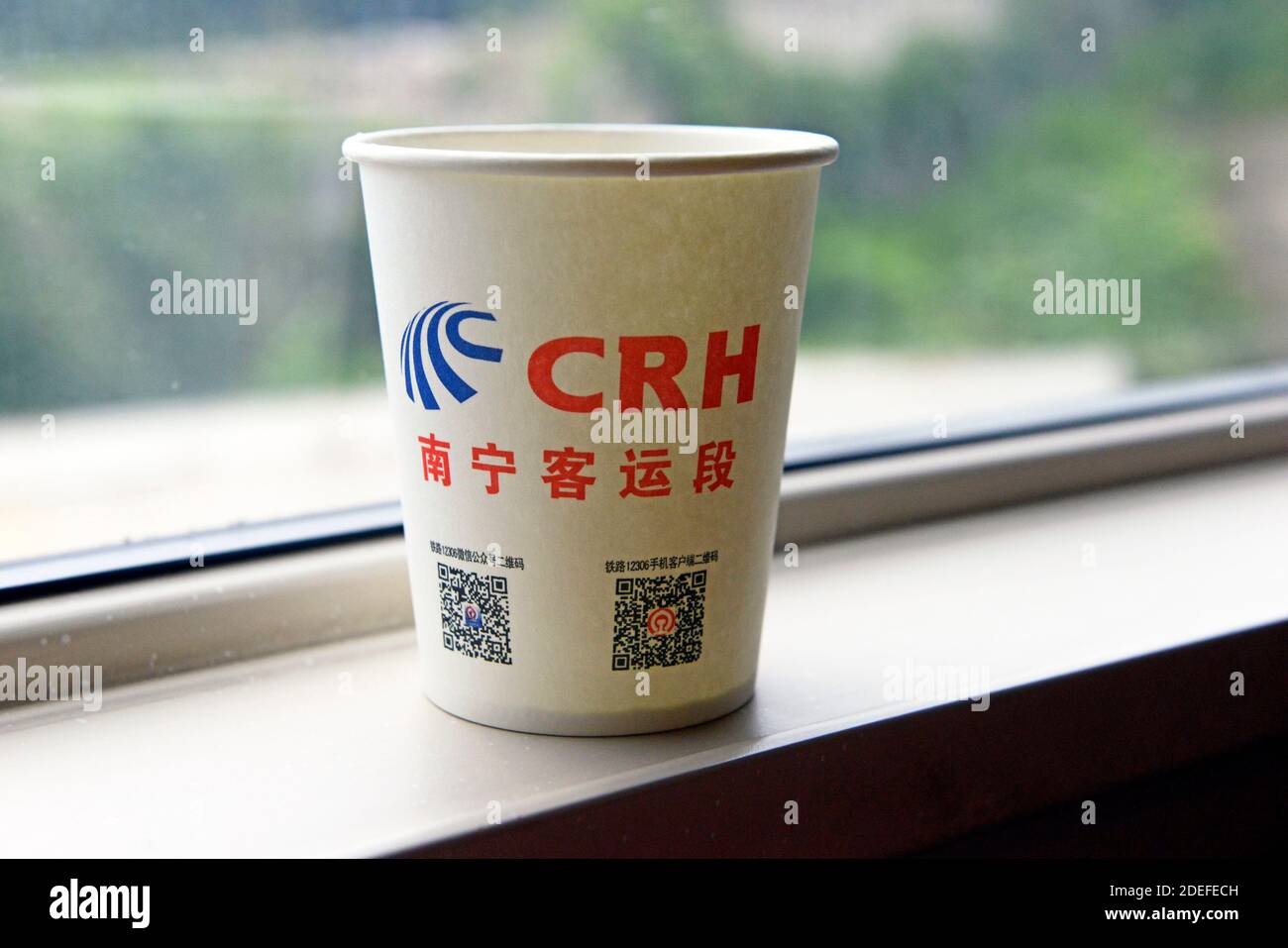 Ein Papierbecher des CRH Nanning Railway Bureau mit QR-Codes ruht in einem Wagen in einem Hochgeschwindigkeitszug in der Nähe von Guiyang, China, auf einem Fensterbrett Stockfoto