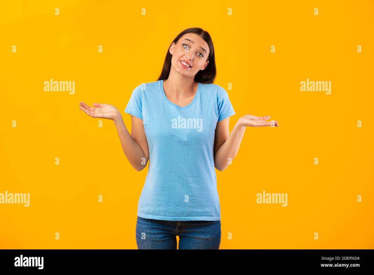 Verwirrt verwirrt verwirrt junge Frau zuckte bei gelben Studio Stockfoto