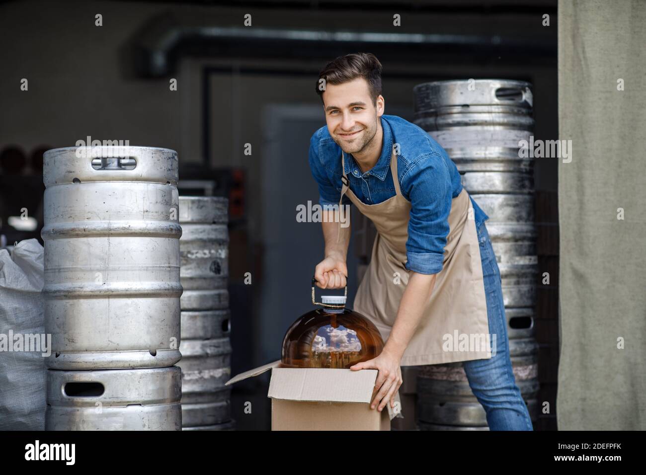 Junger männlicher Brauer mit Fass im Brauereilager und modern Branche Stockfoto