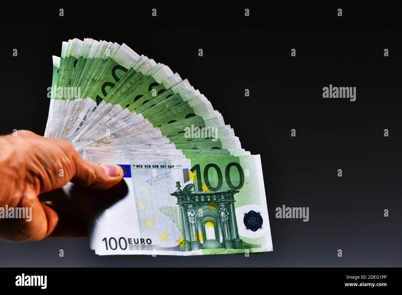 Eine Mann Hand zeigt 20,000 Euro in 100 Euro und 500 Euro Banknoten auf blauem Hintergrund. Kaufen Sie ein neues Auto Stockfoto