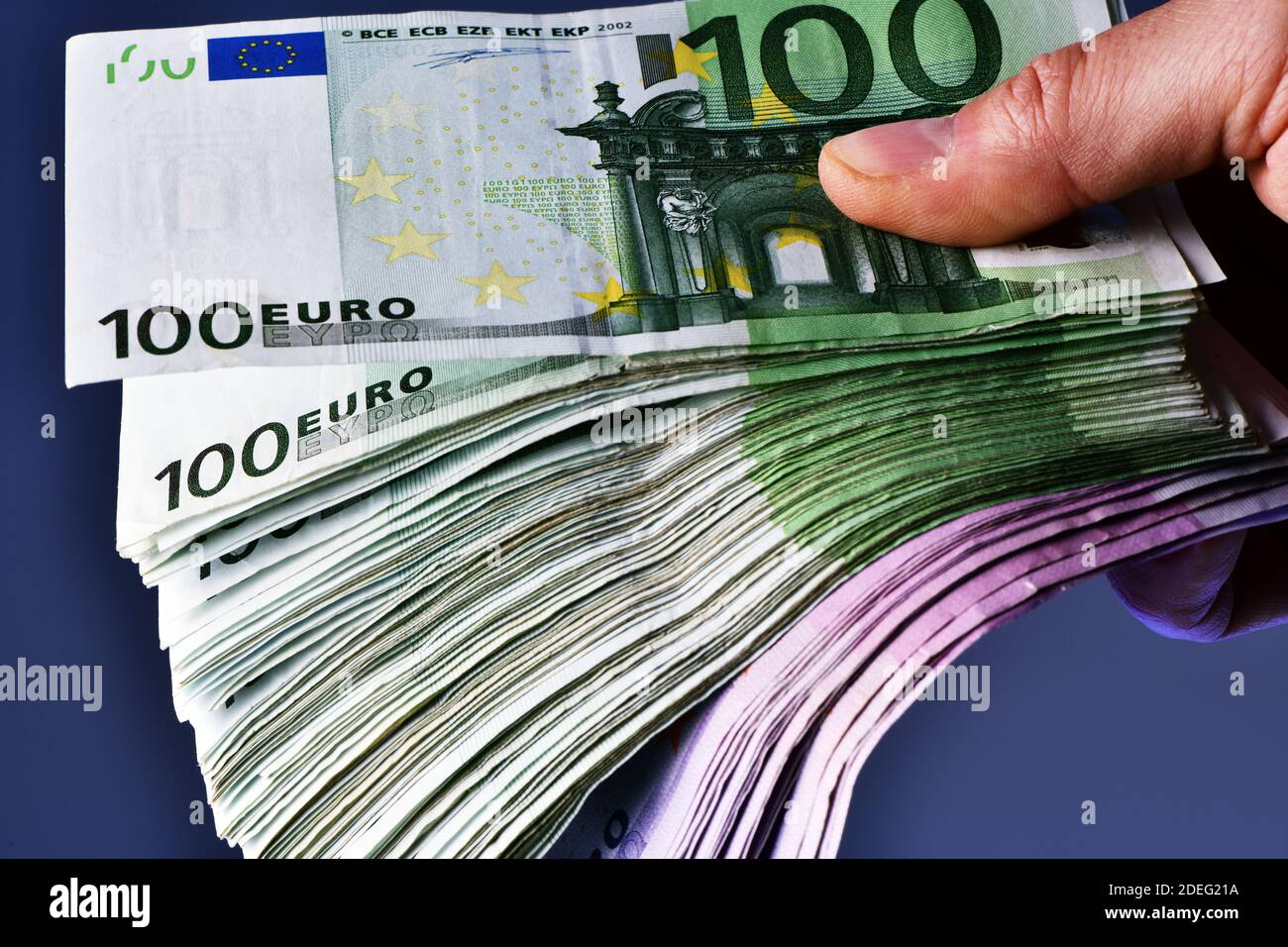 Eine Mann Hand zeigt 20,000 Euro in 100 Euro und 500 Euro Banknoten auf blauem Hintergrund. Kaufen Sie ein neues Auto Stockfoto