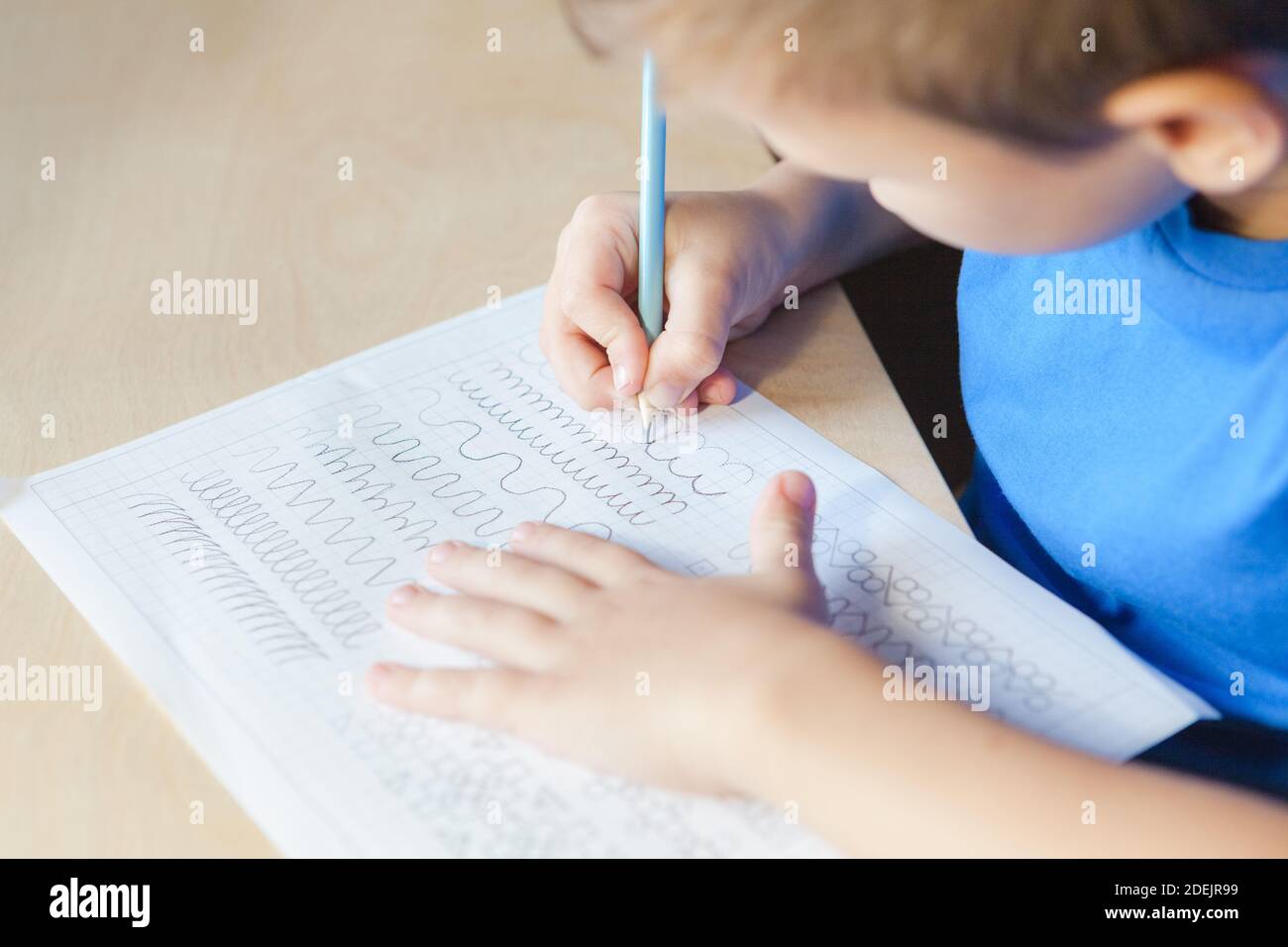 Kind macht Unterricht zu Hause. Kind Junge schriftlich im Arbeitsblatt mit Bleistift. Konzept der Kindererziehung Stockfoto
