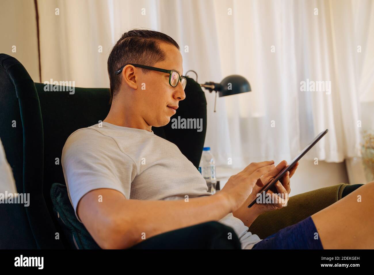 Nahaufnahme von jungen Mann beim Lesen mit digitalen Tablet während Sitzen auf seinem Sofa Couch im Wohnzimmer zu Hause Stockfoto