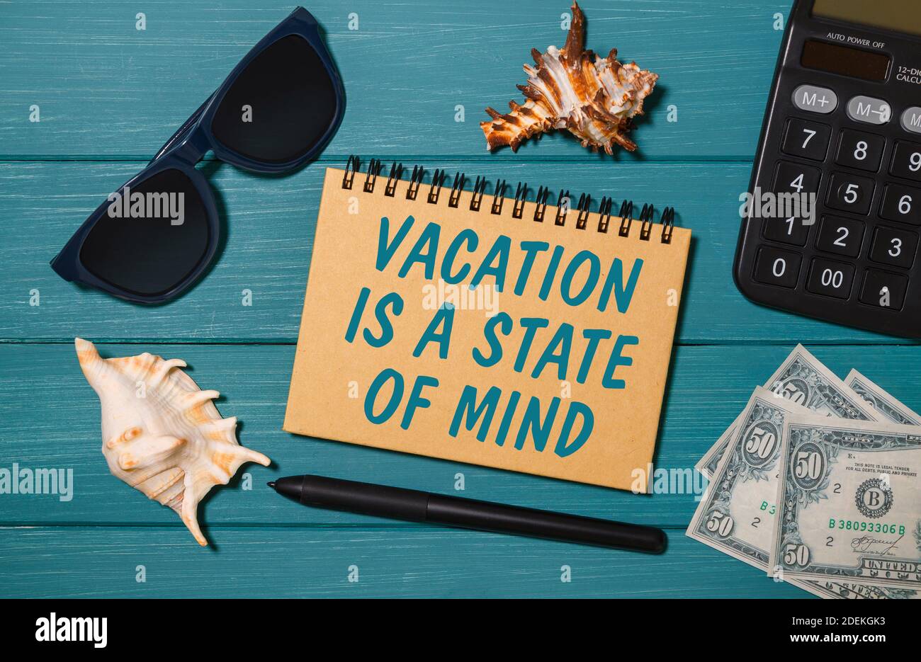 Basteln Sie ein Notizbuch mit den Worten "Urlaub ist ein Geisteszustand", Brille, Geld, Taschenrechner und Muscheln Stockfoto