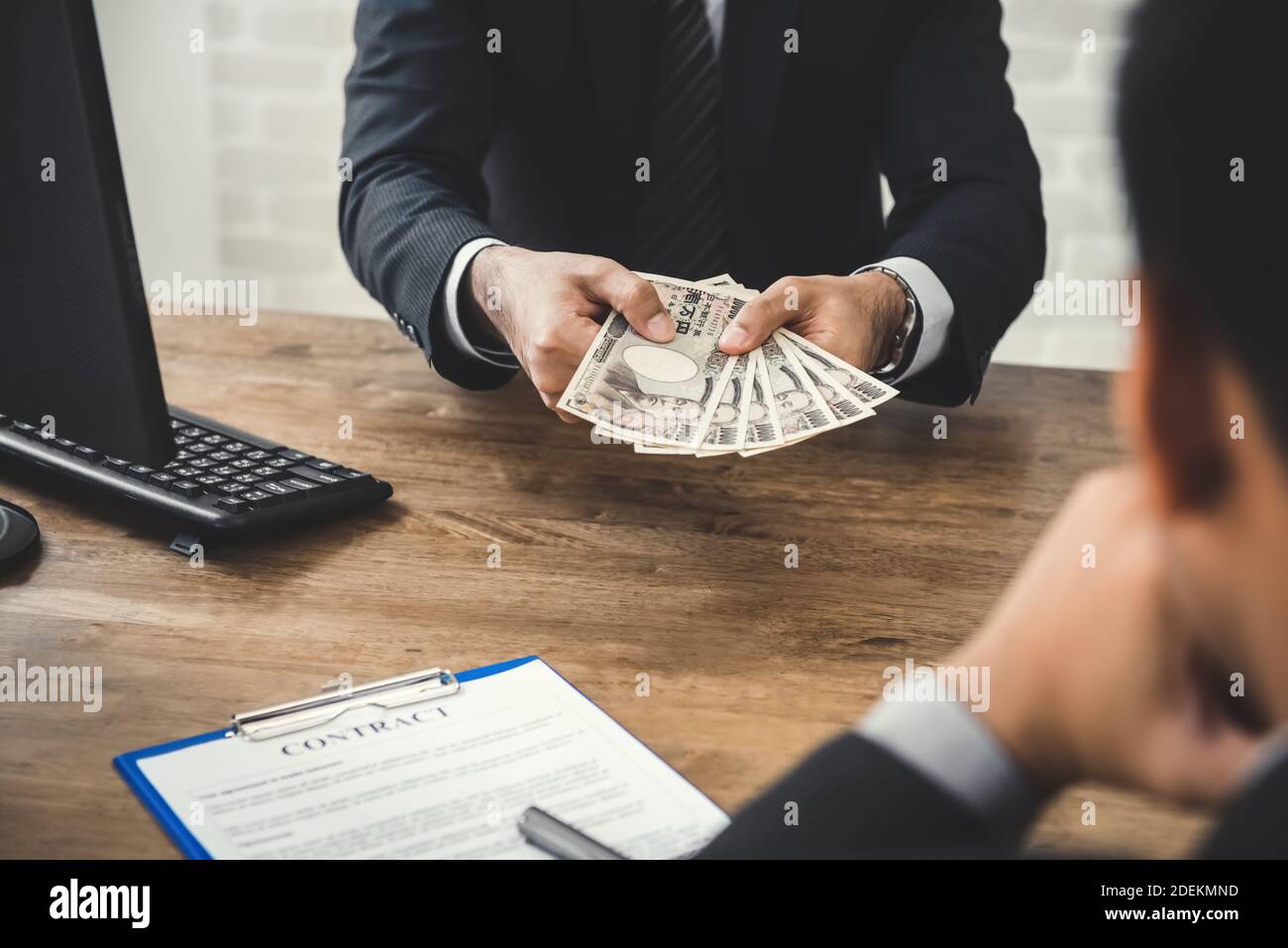 Geschäftsmann, der seinem Partner Geld, japanische Yen-Banknote, gibt, nachdem er einen Vertrag abgeschlossen und am Schreibtisch unterschrieben hat Stockfoto