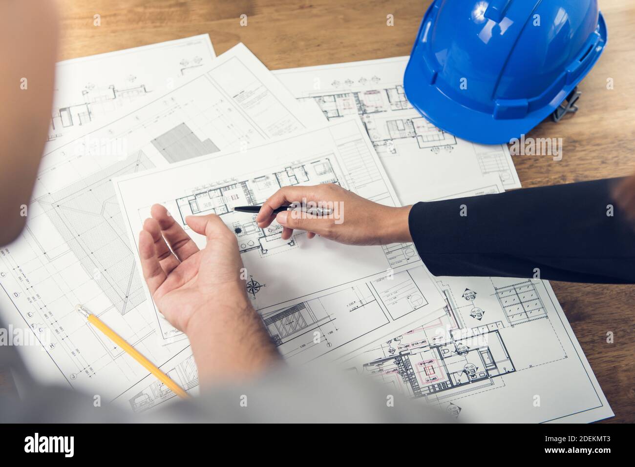 Ingenieur und Architektenteam besprechen Grundrissplan für neue Die Entwicklung läuft vor Ort mit blauem Schutzhelm Tabelle Stockfoto