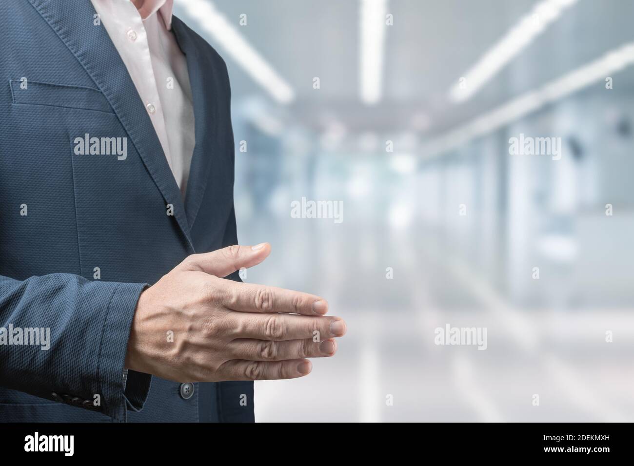 Selbstbewusster Geschäftsmann, der seine Hand zum Gruß ausstreckt. Geschäftsmann streut seine Hand für einen Handschlag auf verschwommenem Bürohintergrund. Geschäftsmann in einem Stockfoto