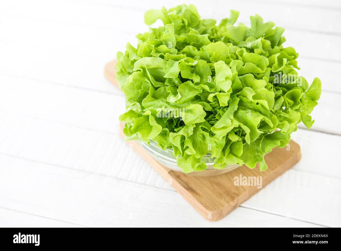 Frische Bio gesunde grüne Eiche Salat Gemüse in einer Glasschüssel auf Holzplatte in der Küche, bereit, als Salat oder kochen zu essen Stockfoto