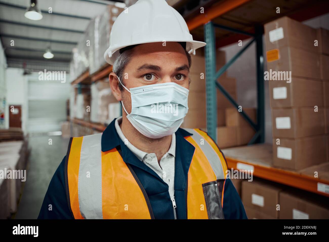 Nahaufnahme eines männlichen Fabrikarbeiters in Sicherheitsmaske Im Industrielager Stockfoto