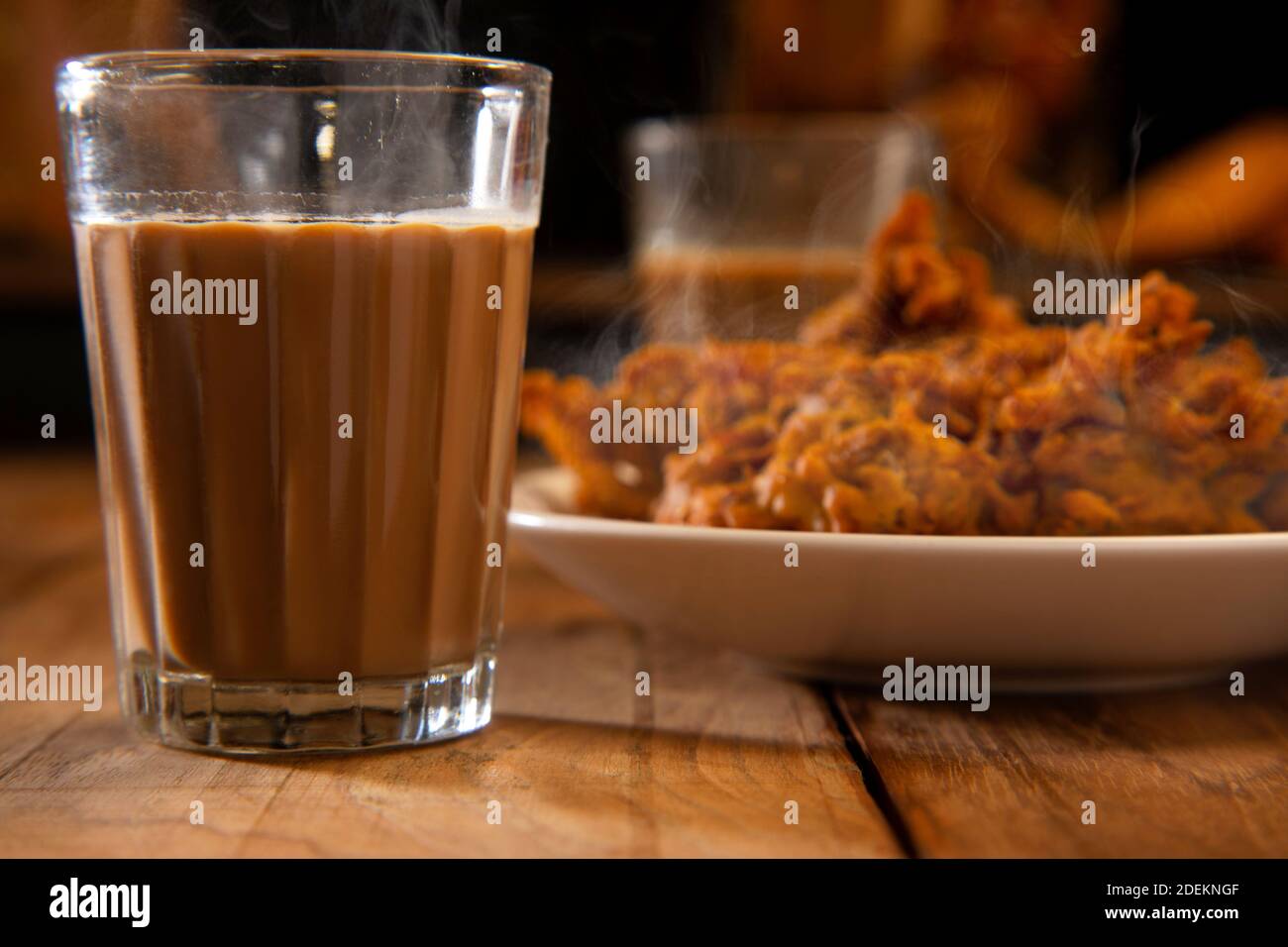 Teeglas vor einem Teller mit gefüllt gehalten Pakoras auf einem Tisch Stockfoto