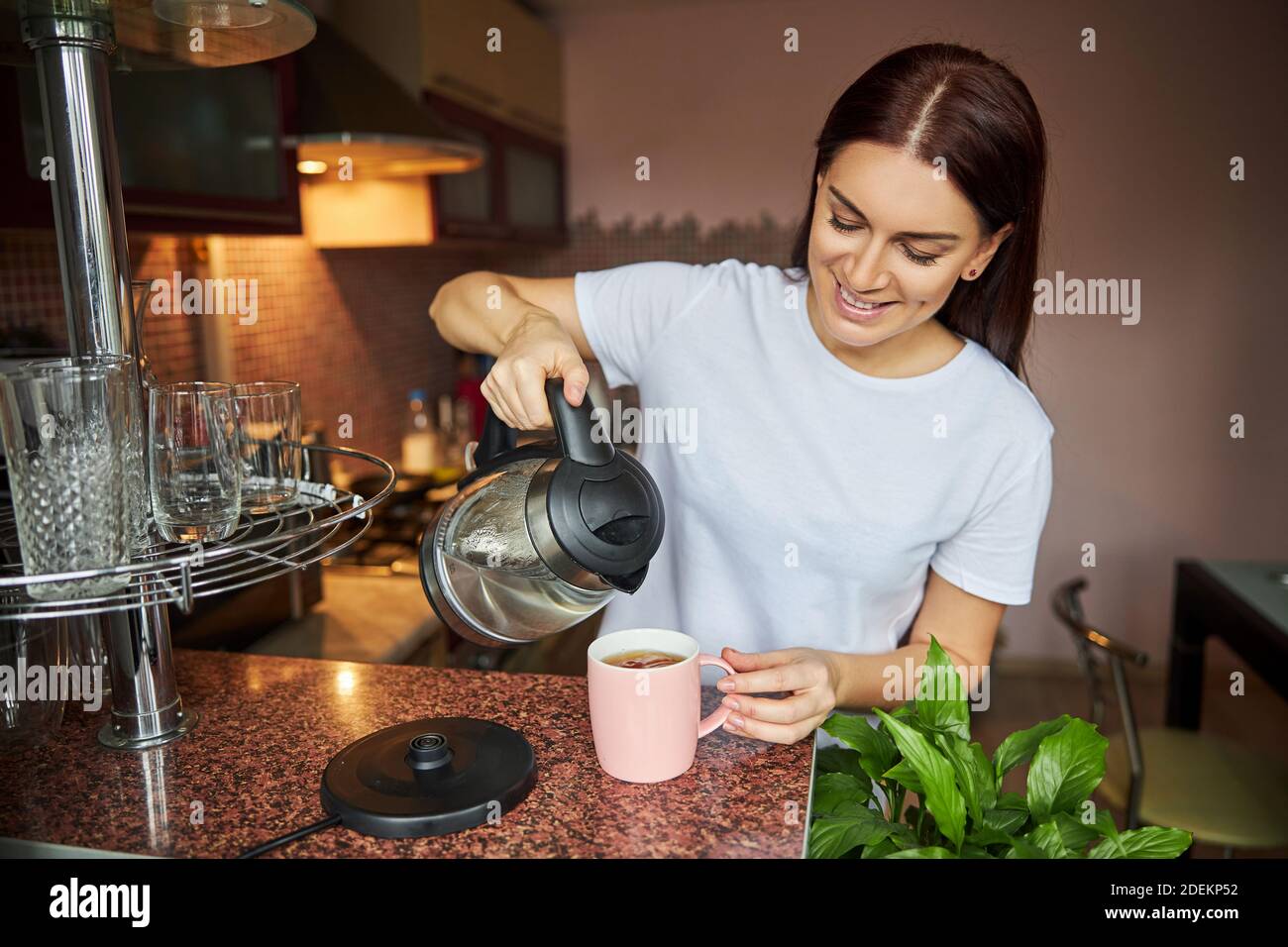 Frau, die ihrem Tee mehr Wasser zugab Stockfoto