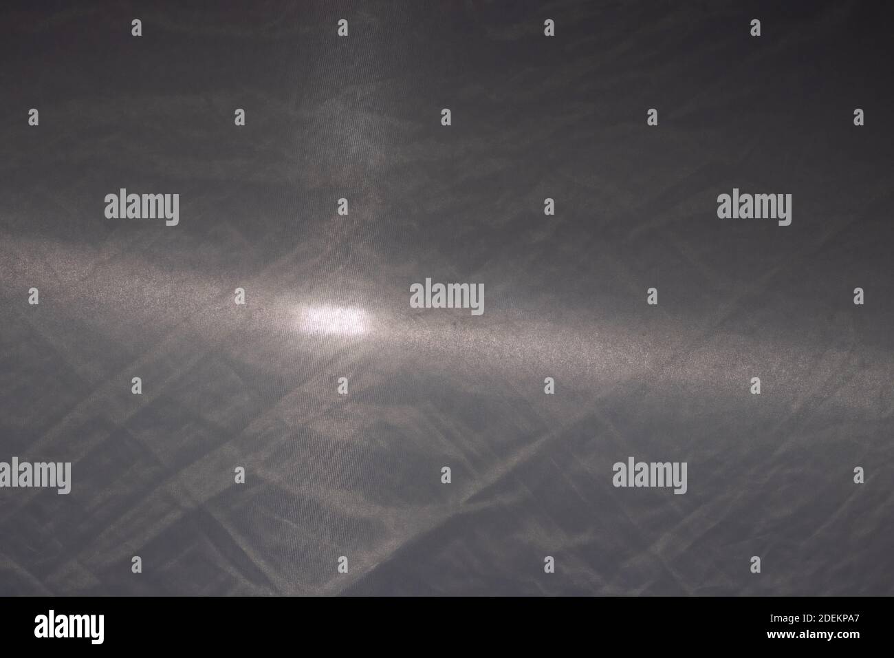 Textur aus grauem Stoff mit einem Strahl von Taschenlampe Licht, grauer Hintergrund. Stockfoto