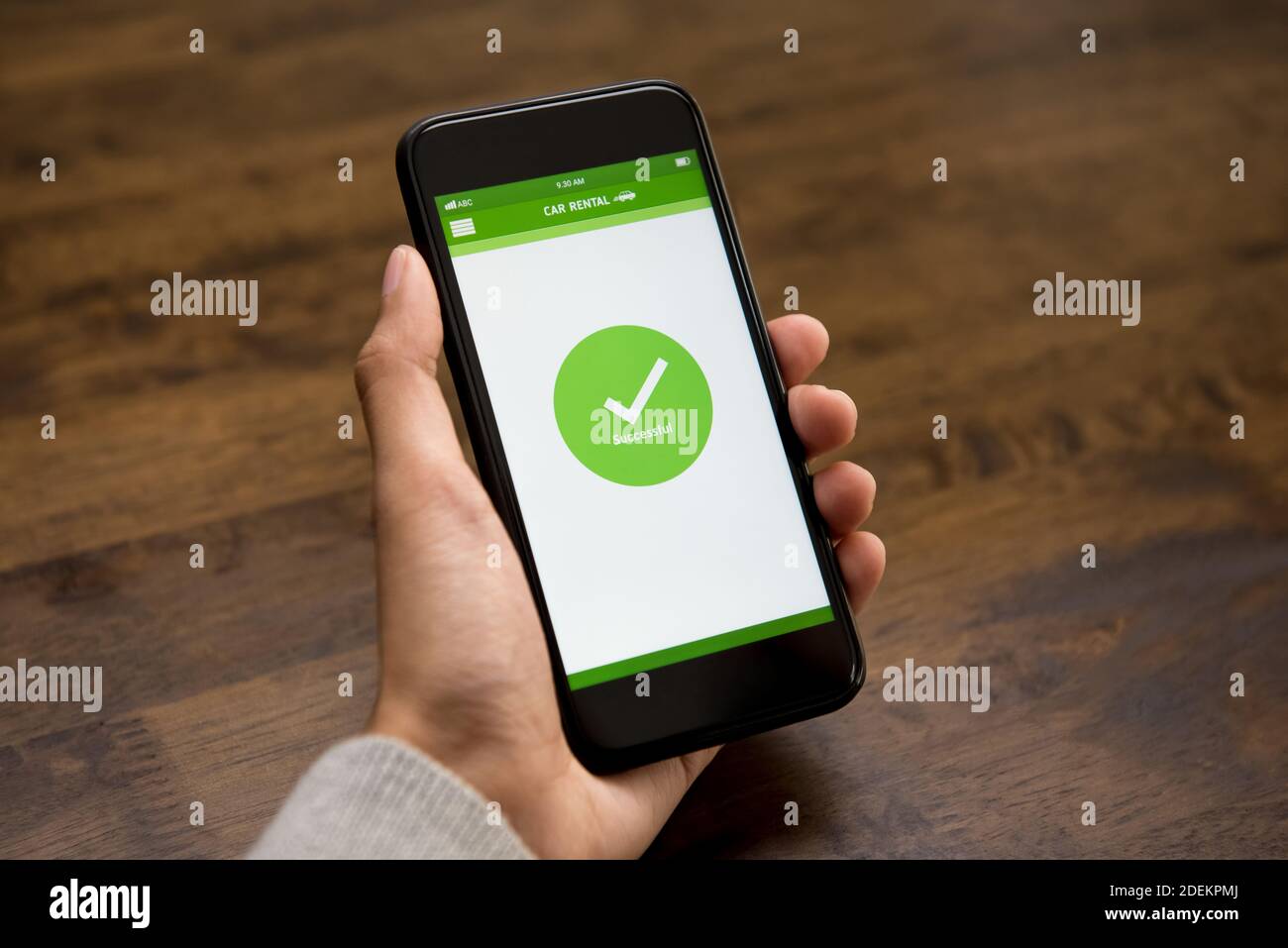 Auf dem Smartphone-Bildschirm wird das Bestätigungszeichen für eine erfolgreiche Online-Autovermietung angezeigt Nach der digitalen Buchung durch eine Kundin Stockfoto