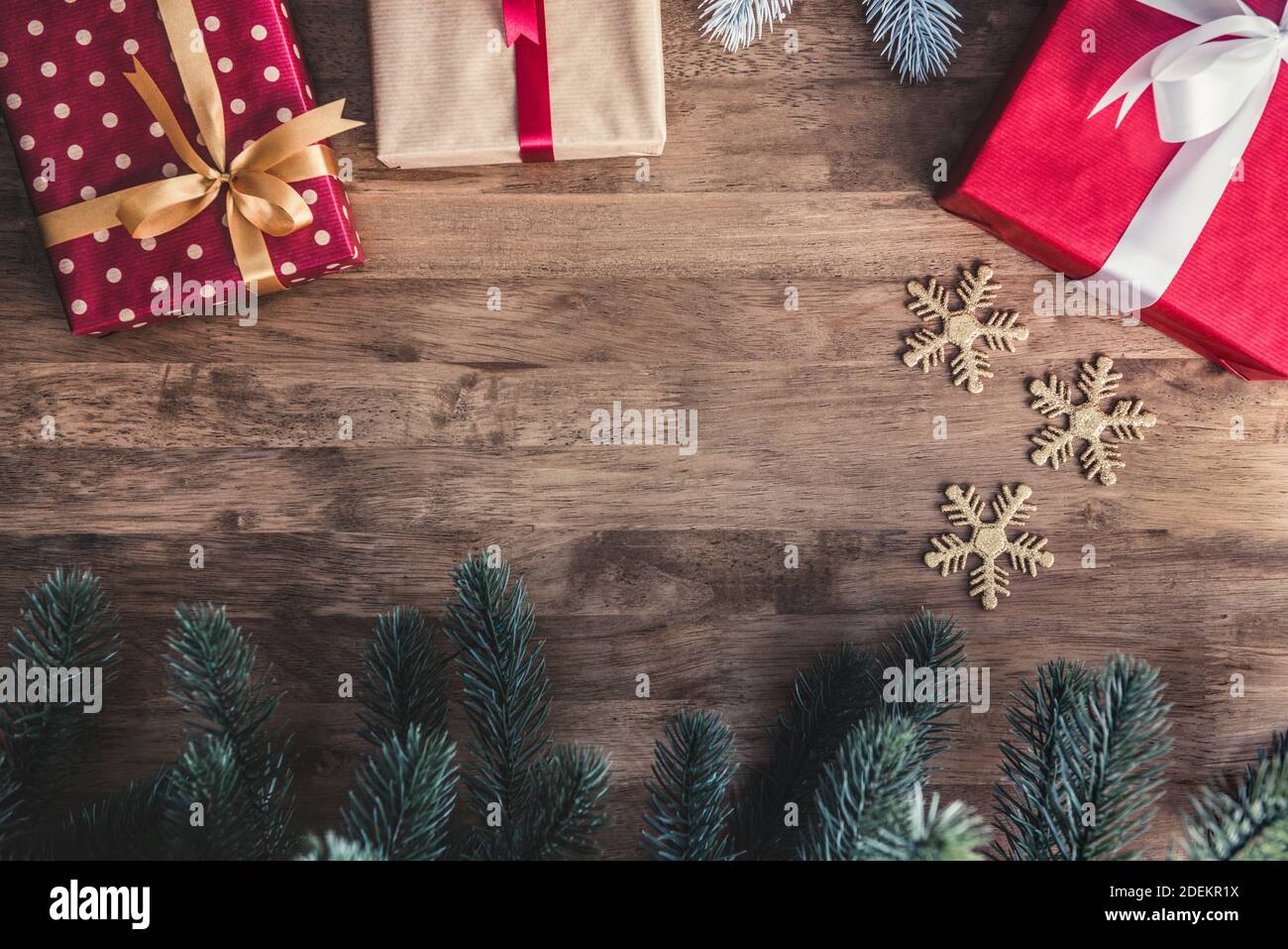 Draufsicht auf bunte Geschenkboxen auf einem Holztisch mit Kiefer und Dekorationsartikel, Bordüre Design Weihnachten Hintergrund mit Kopieplatz in der Mitte Stockfoto