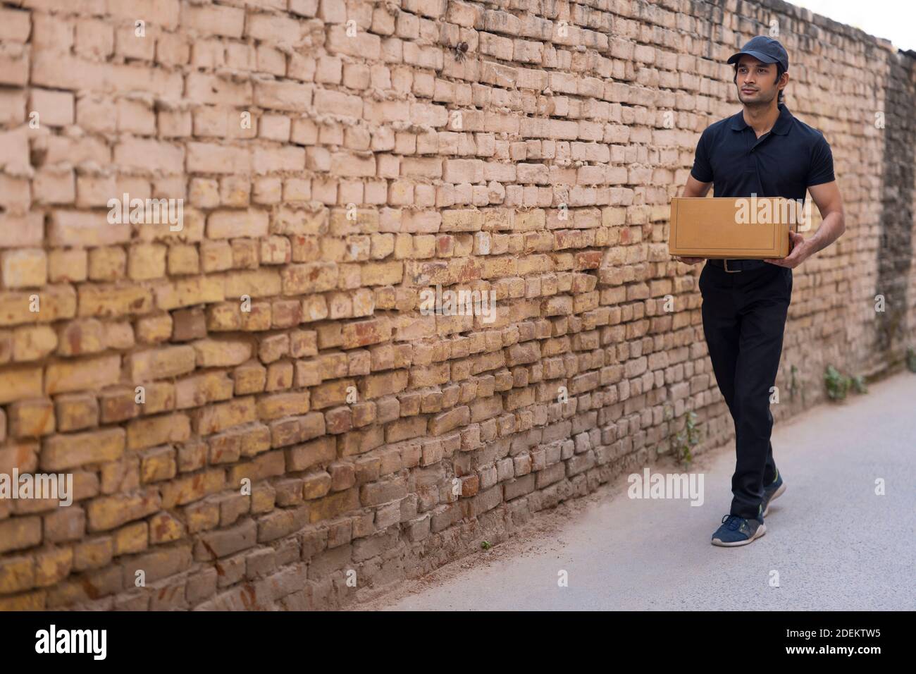 Kurierjunge, der mit einem Paket in der Hand geht Stockfoto