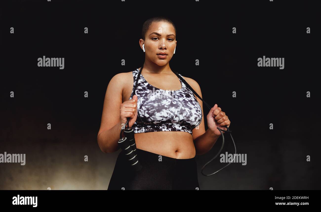 Frau in Fitnesskleidung, die sich während ihres Workouts entspannt und ein Seilspringen hält. Fitness-Frau, die draußen steht und ein Seil hält und ansieht Stockfoto