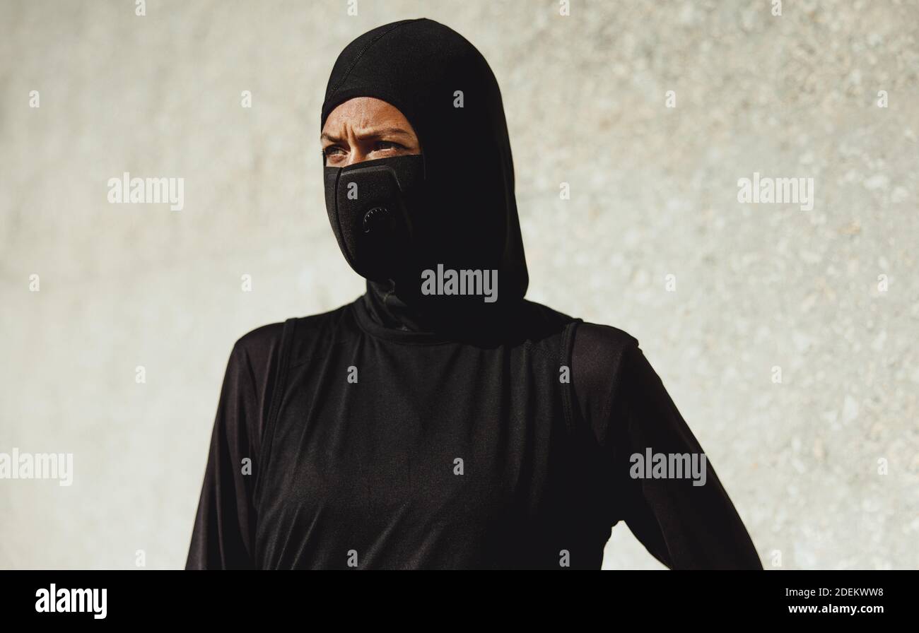 Nahaufnahme der muslimischen Frau in Sportkleidung und Gesichtsmaske im Freien. Weiblich in Hijab Training Outfit Pause nach dem Training. Stockfoto
