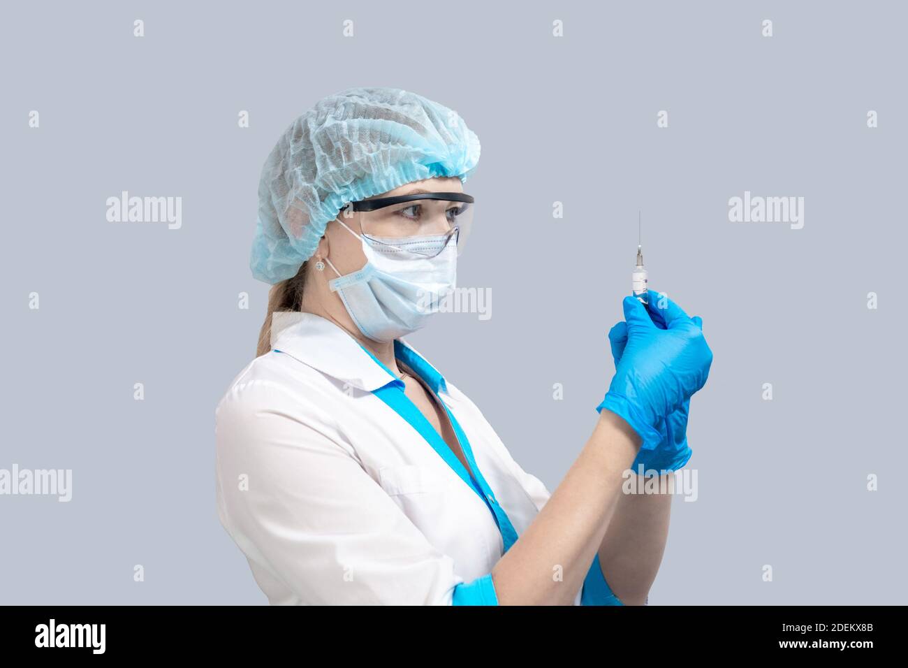Krankenschwester auf grauem Hintergrund in Schutzmaske und Brille, hält eine Spritze mit einem Impfstoff. Medizin und Gesundheitswesen. Coronavirus-Behandlung. Stockfoto