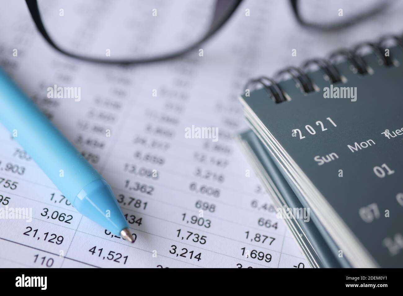 Kugelschreiber und Kalender liegen auf Dokumenten mit Zahlen aus der Nähe Stockfoto