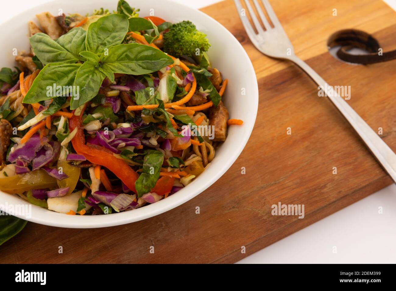 Blick auf die Schüssel mit Salat und Basilikumblättern Auf Holzbrett Stockfoto