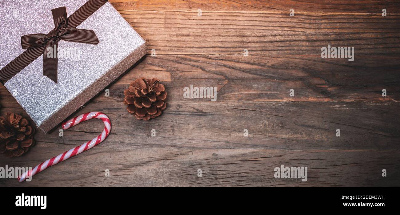 Silbernes glänzendes Weihnachtsgeschenk und Zuckerrohr auf Holz. Stockfoto