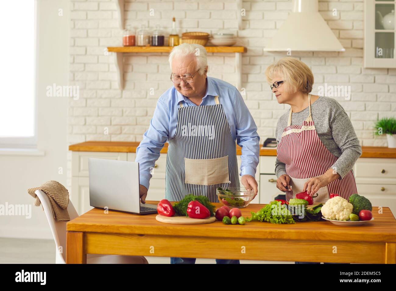 Glückliches Senior-Paar, das Video Rezept und machen gesunde Vegetarier Essen zu Hause Stockfoto