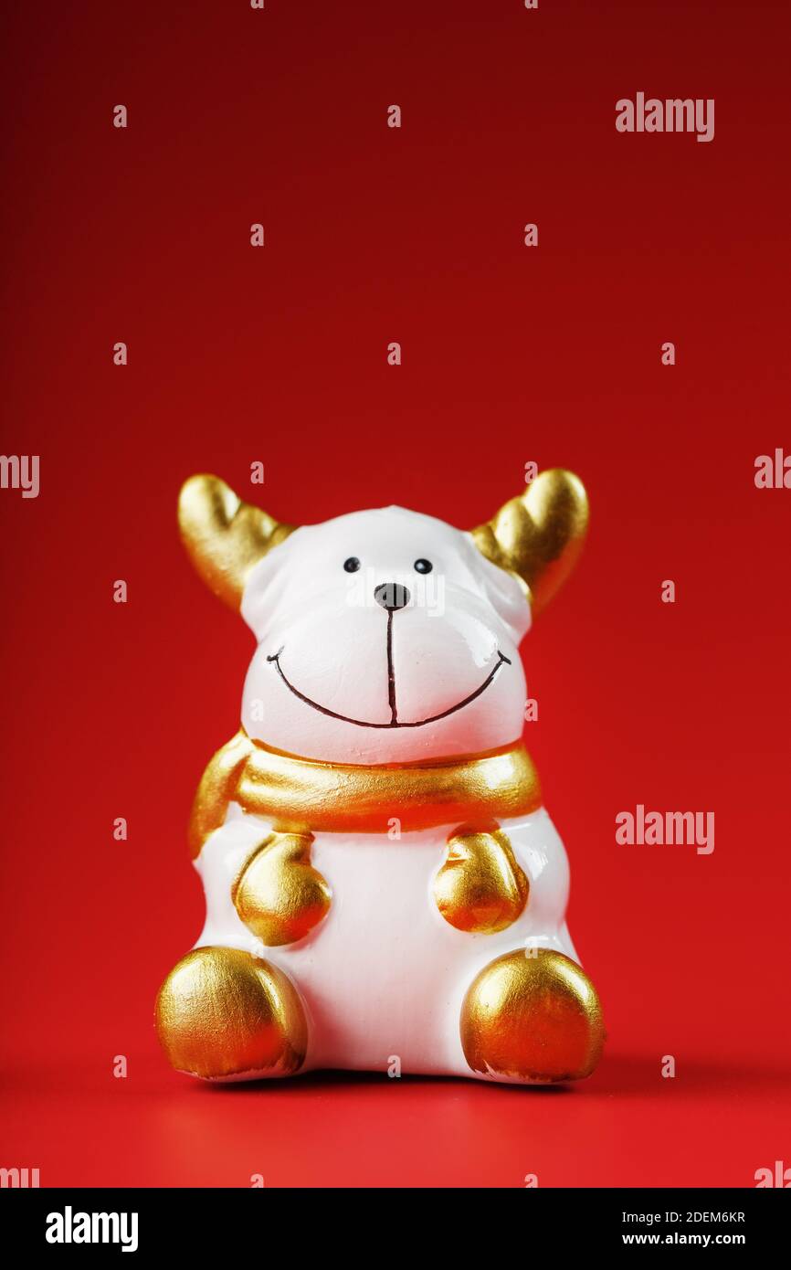 Weihnachtskuhfigur auf rotem Hintergrund. Symbol des neuen Jahres des Bullen 2021. Isolieren Stockfoto