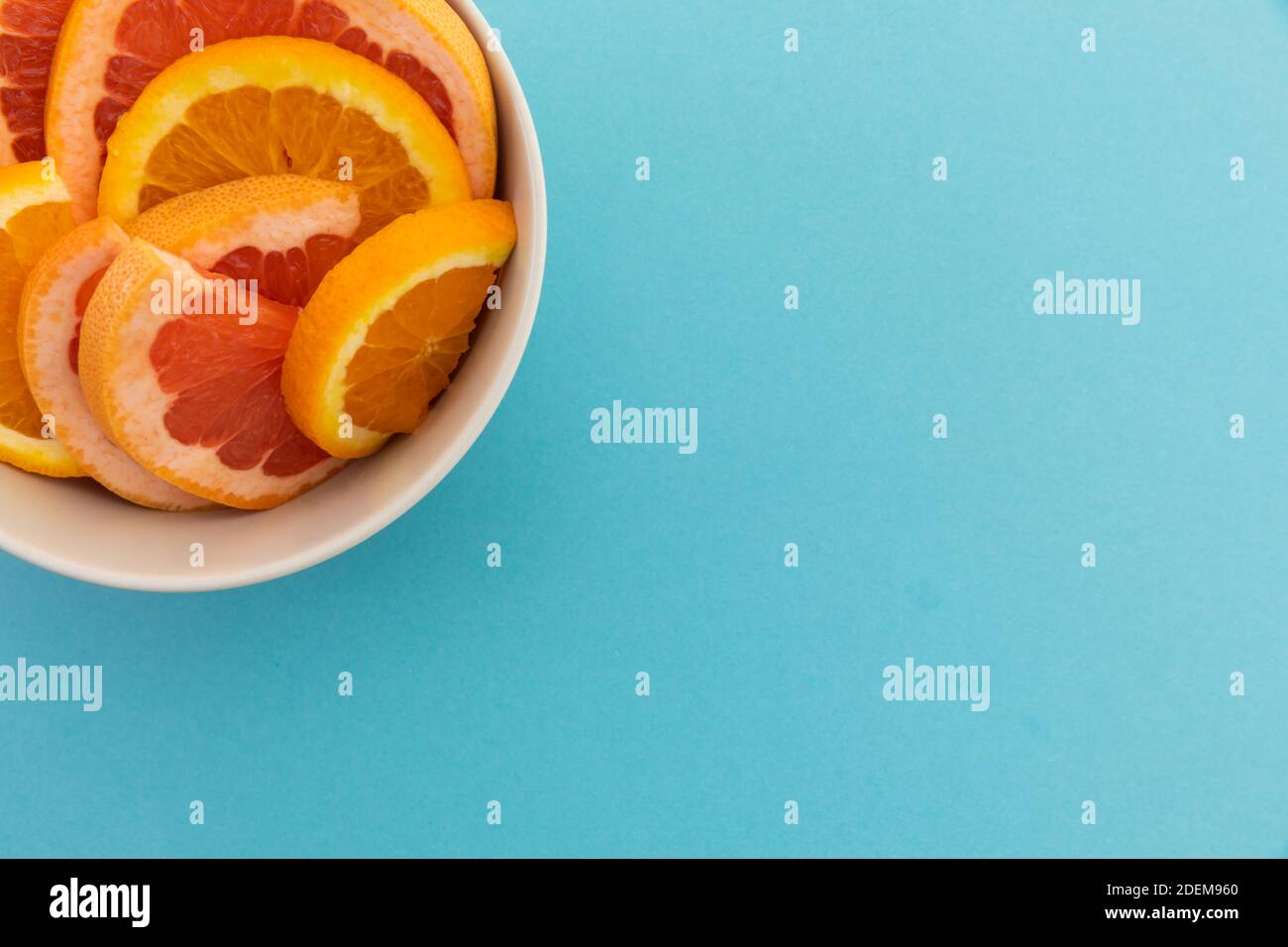 Blick in die Schüssel mit frisch geschnittenen Orangenscheiben Auf blauem Hintergrund Stockfoto