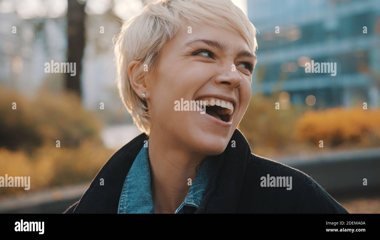 Schöne aufgeregt junge kaukasische blonde Frau lachen im Stadtpark. Hochformat. Hochwertige Fotos Stockfoto