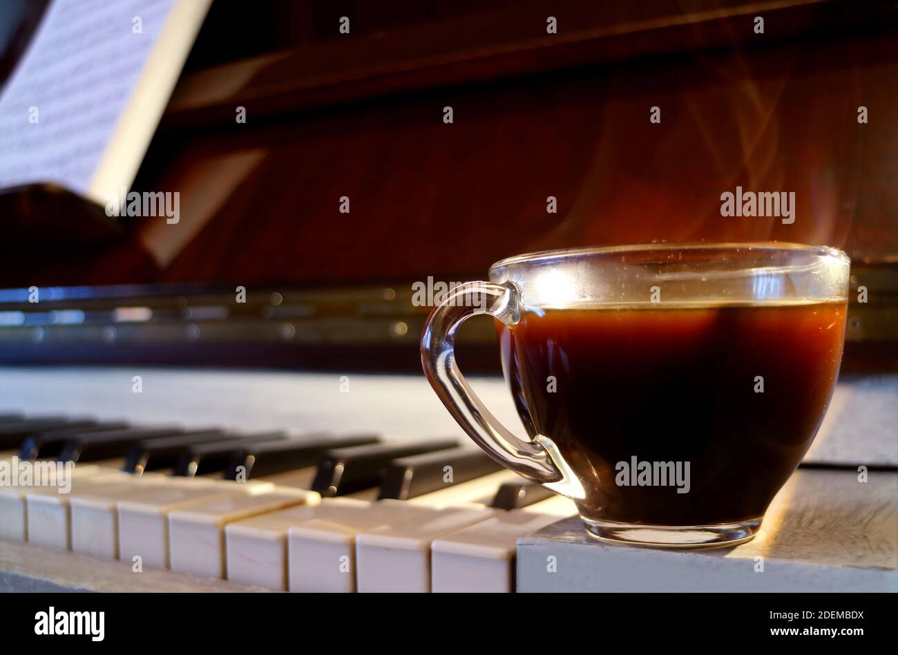 Nahaufnahme eine Tasse heißen Kaffee mit Rauch auf der Klavier mit verschwommener Notenblatt Stockfoto