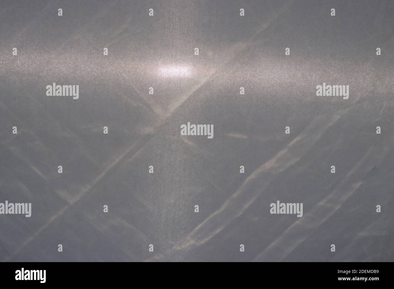 Textur aus grauem Stoff mit einem Strahl von Taschenlampe Licht, grauer Hintergrund. Faltiges Tuch Stockfoto