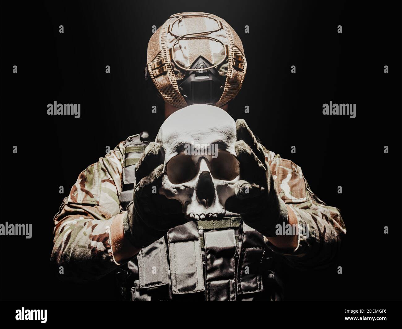 Foto eines voll ausgerüsteten Soldaten in Panzerweste, Helm und Handschuhen mit menschlichem Schädel. Stockfoto