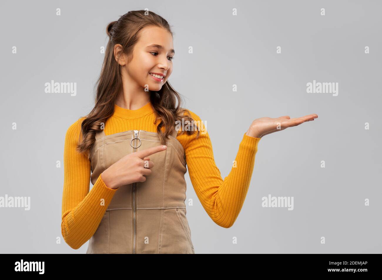 Glückliches Teenager-Mädchen hält etwas auf leere Hand Stockfoto