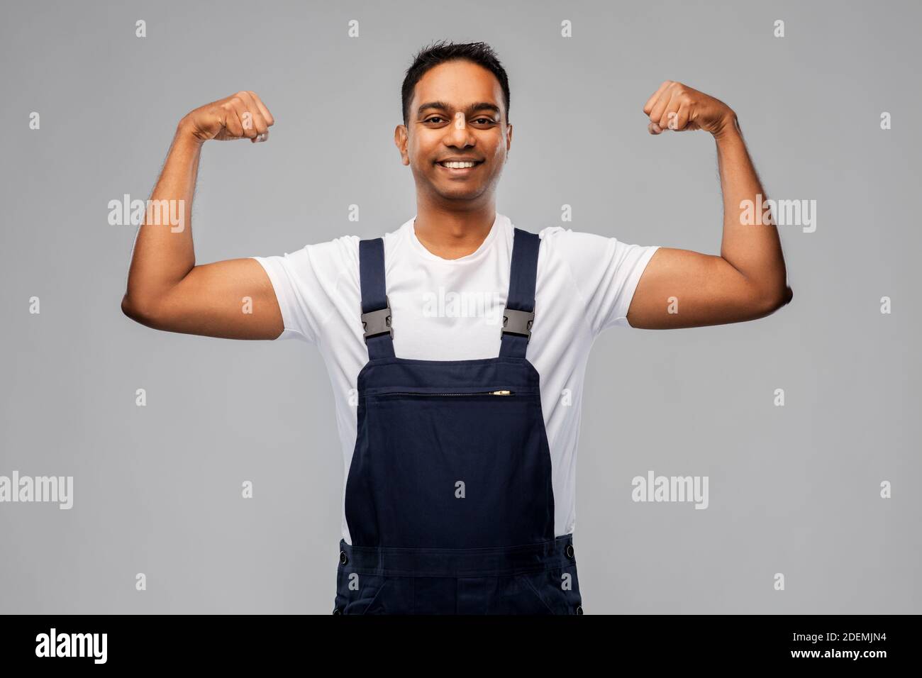 Lächelnder indischer Arbeiter oder Baumeister, der seine Macht zeigt Stockfoto