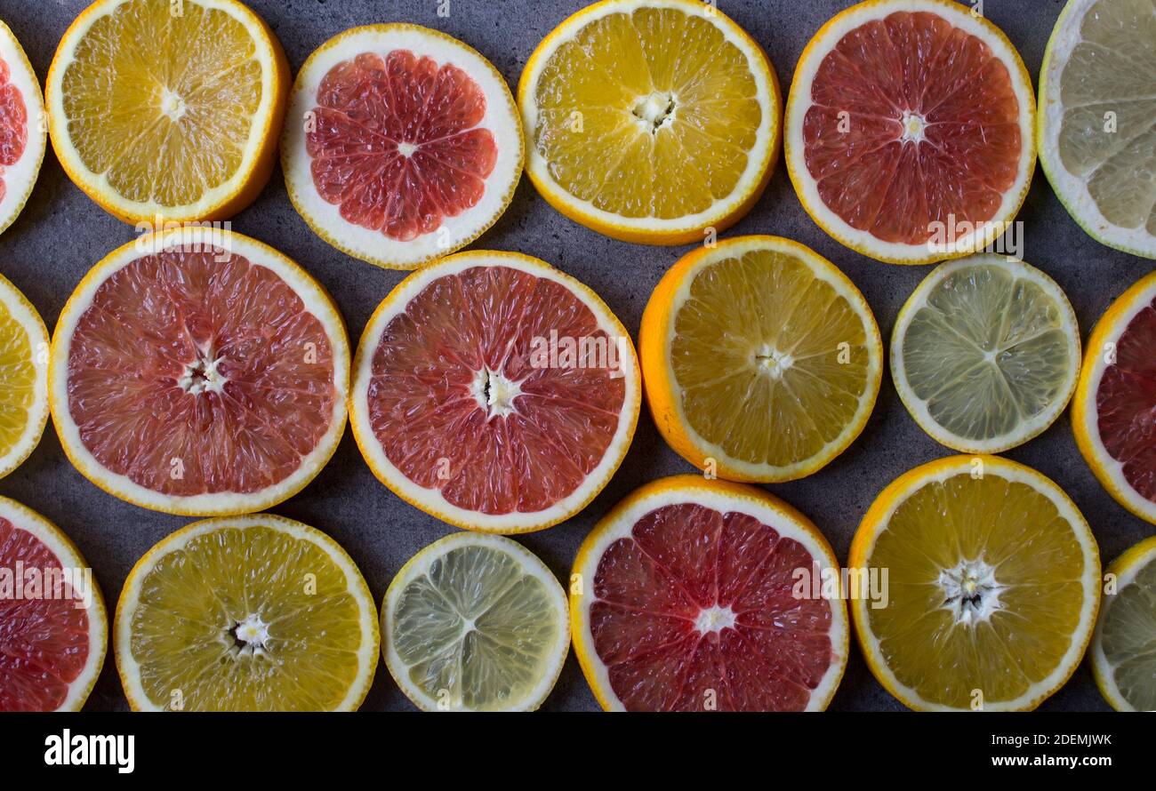 Rot-orange Scheiben auf einem Tisch. Nahaufnahme mit Fruchtstruktur. Dunkelgrauer Hintergrund mit Kopierbereich. Stockfoto