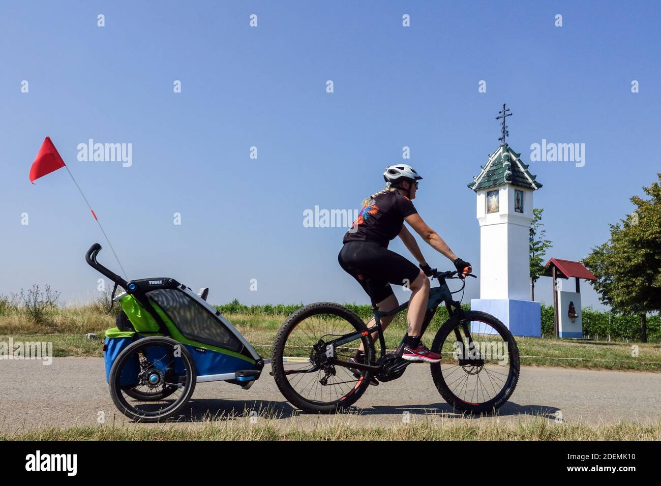Eine Frau auf einem Fahrrad, die einen Fahrradanhänger für Kinder schleppt Mähren Tschechische Republik Stockfoto