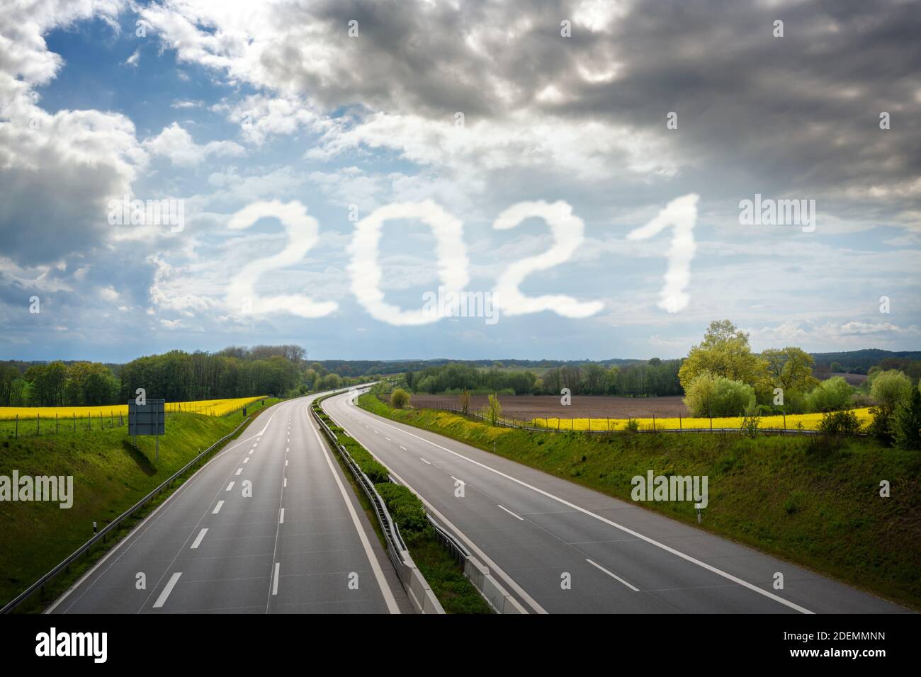 Leere Autobahn führt durch eine ländliche Landschaft zum Neujahr Nummer 2021 geschrieben in den wolkigen Himmel, kopieren Raum Stockfoto