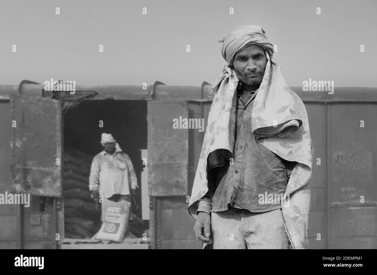 Mann trägt nur Kopftuch als Schutz eingesetzt, um Taschen aus Zement von der Bahn auf Lastwagen in Mathura, Uttar Pradesh, Indien zu bewegen. Stockfoto