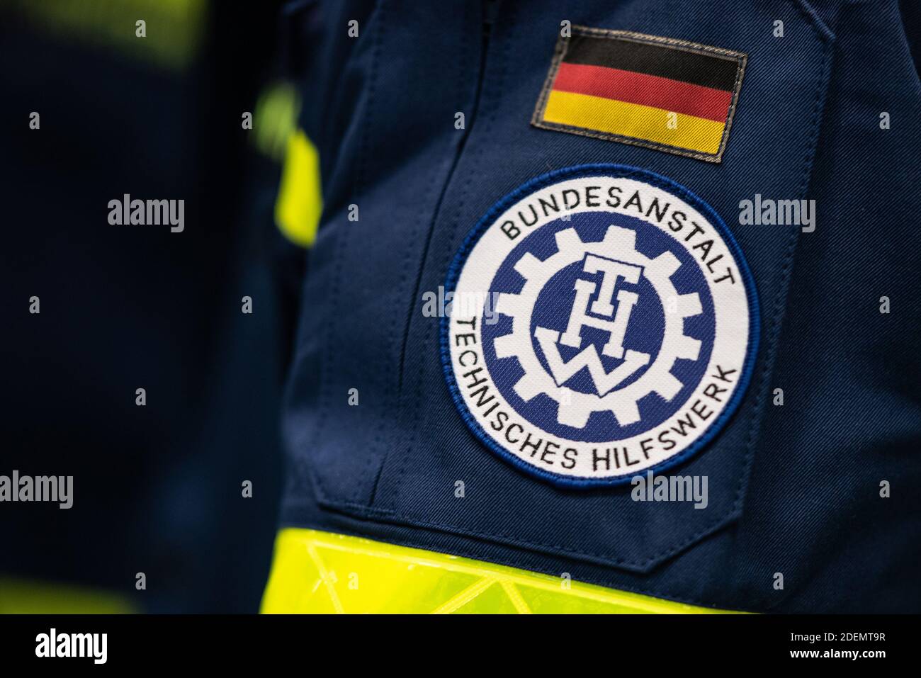 01. Dezember 2020, Hessen, Eschwege: Das Logo des Technischen Hilfswerks (THW) ist auf dem Arm eines Helfers beim Bau eines Impfzentrums in der Sporthalle der Oberschule zu sehen. In Eschwege im Kreis Werra-Meissner wird vom Bezirk und verschiedenen Katastrophenschutzorganisationen ein Impfzentrum eingerichtet. Foto: Swen Pförtner/dpa Stockfoto