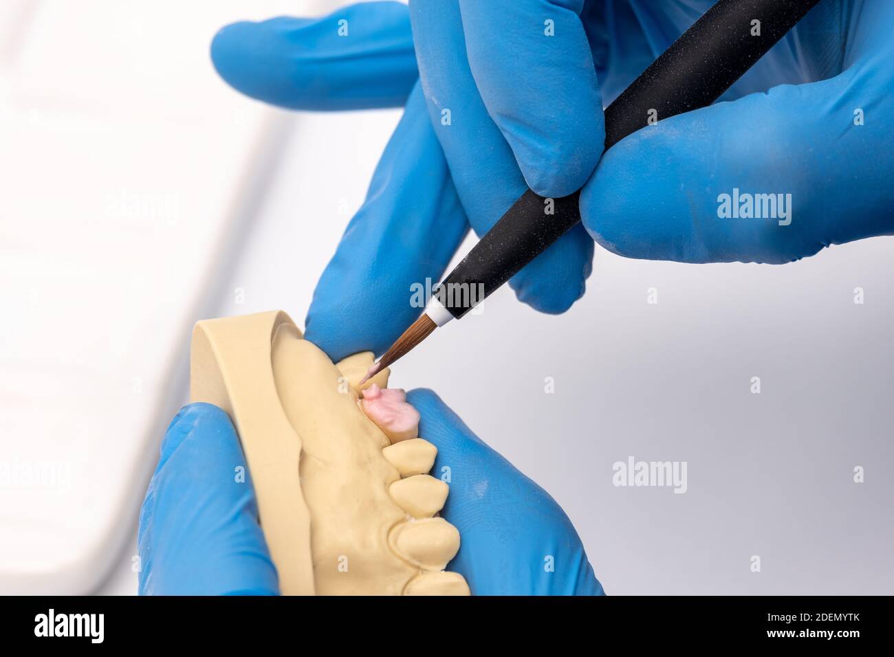 Zahntechniker mit einer Bürste mit keramischen Zahnimplantaten in seinem Labor. Stockfoto