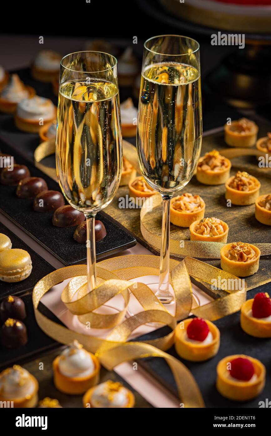 Zwei Gläser Champagner und eine Auswahl an süßen und herzhaften Snacks werden während einer Veranstaltung serviert. Stockfoto