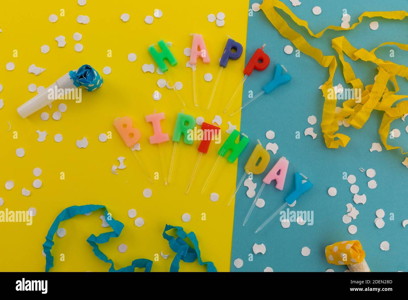 Happy Birthday Kerzen mit Konfetti und Party-Streamer auf blau Und gelb Stockfoto