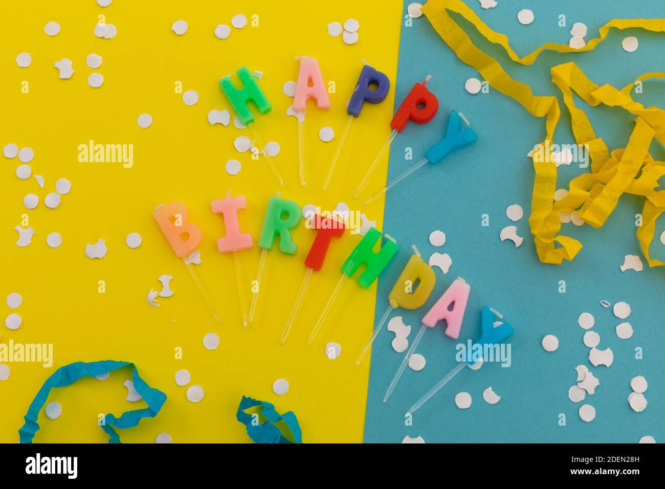 Happy Birthday Kerzen mit Konfetti und Party-Streamer auf blau Und gelb Stockfoto