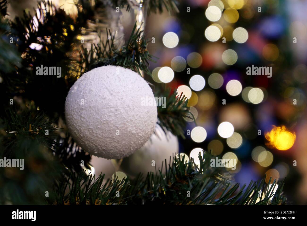 Weihnachtsbaum mit Dekorationen auf verschwommenem Licht Hintergrund. Weiße Kugel auf einem Zweig, Neujahrsfeier Stockfoto